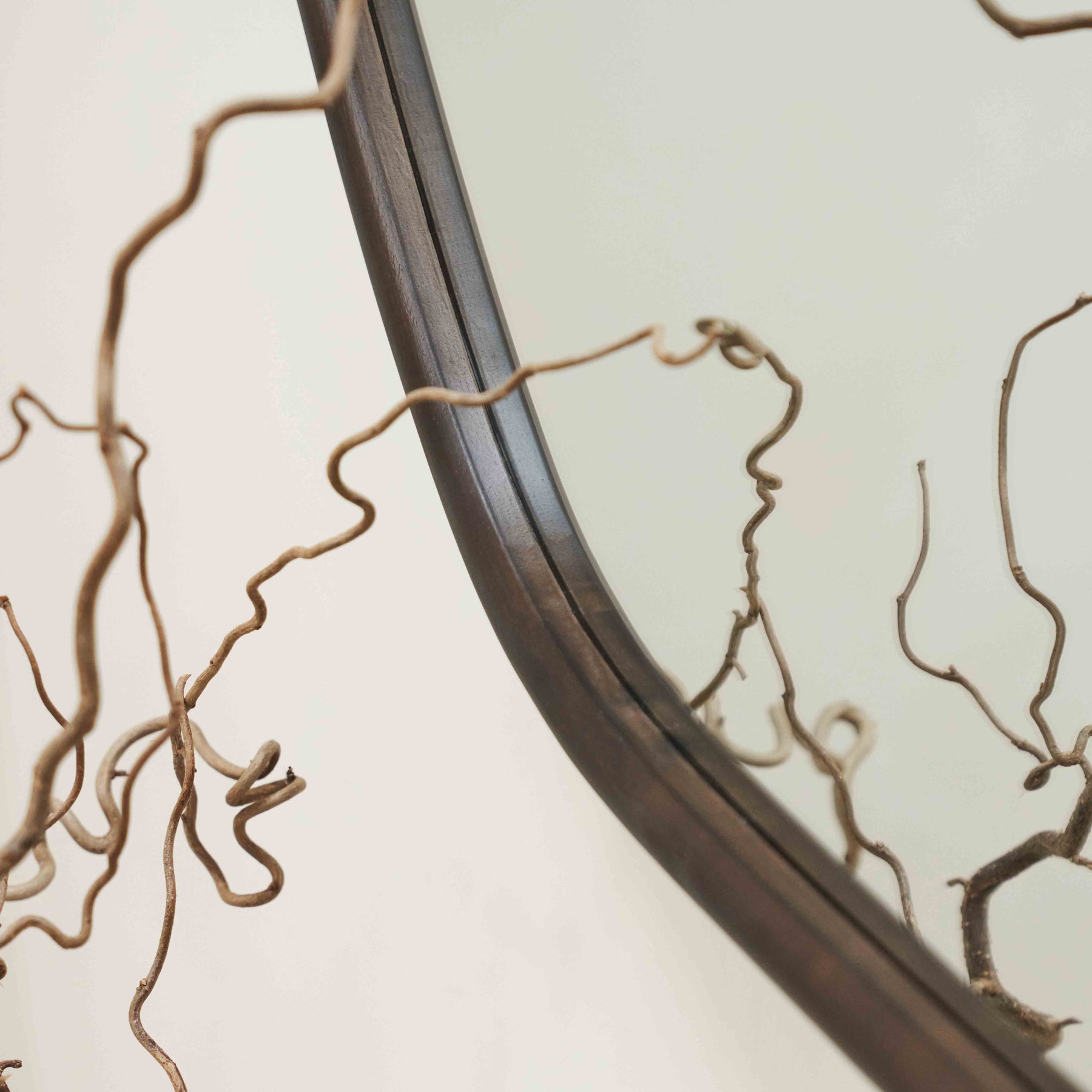 Closeup of Organic irregular walnut-coloured wooden wall mirror