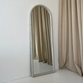 Large arched concrete mirror leaning against wall
