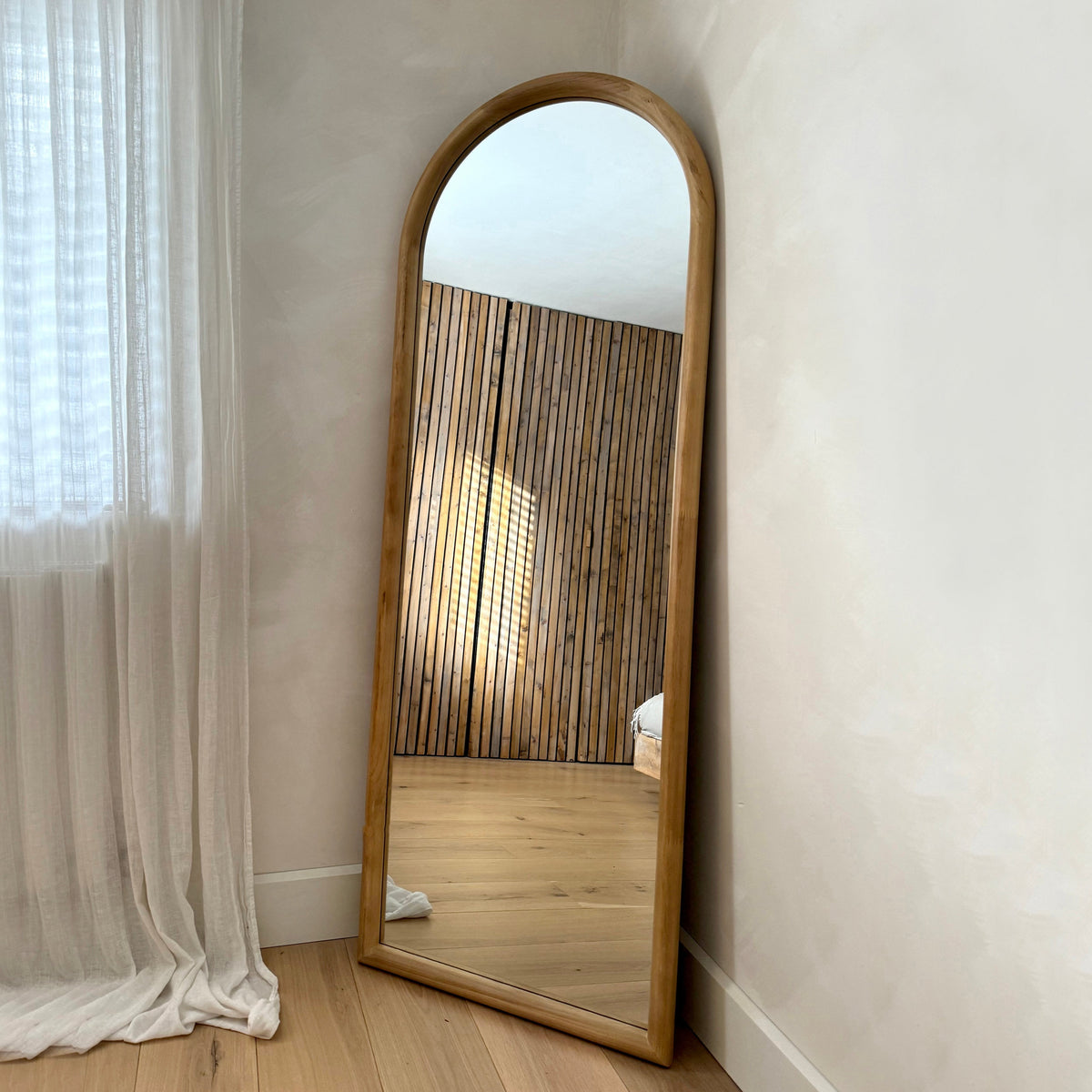 Full length large arched natural mirror leaning against wall