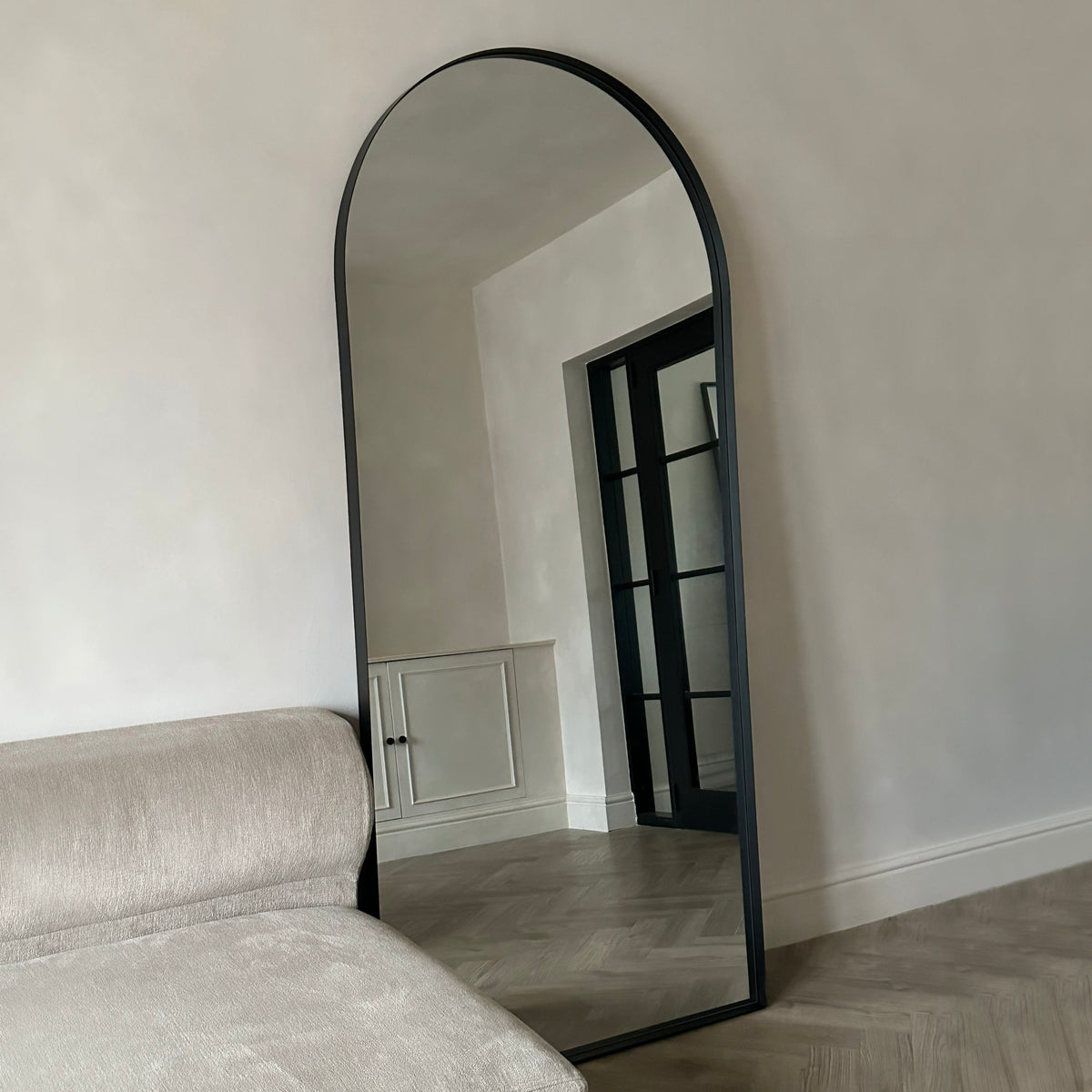 Full length arched black extra large metal mirror leaning against wall