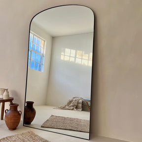 Full length black extra large metal mirror leaning against wall