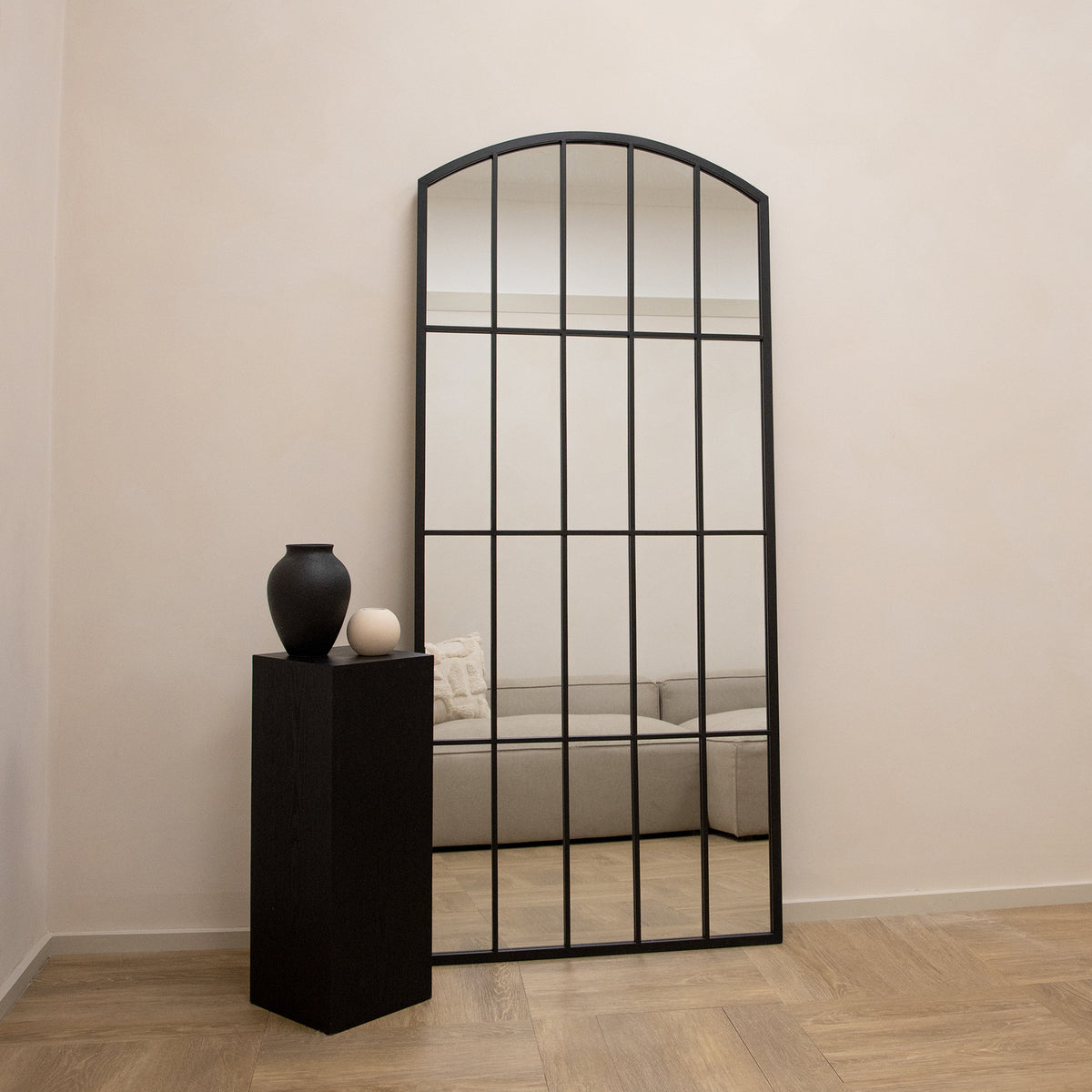 Full length black metal window mirror leaning against wall with ceramics