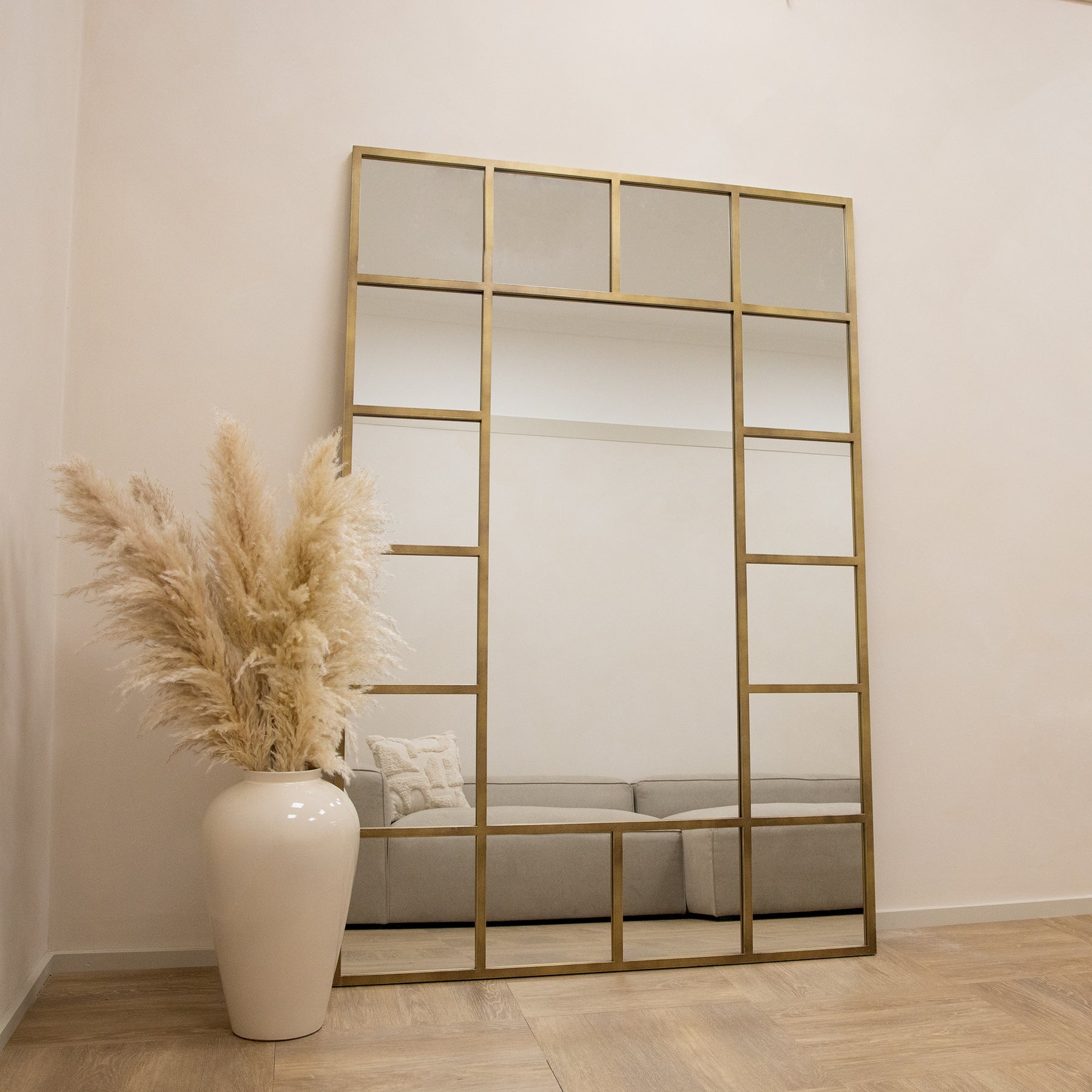 Gold industrial full length metal window mirror beside vase