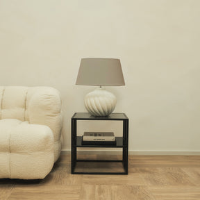 Textured ceramic based table lamp beige shade beside sofa