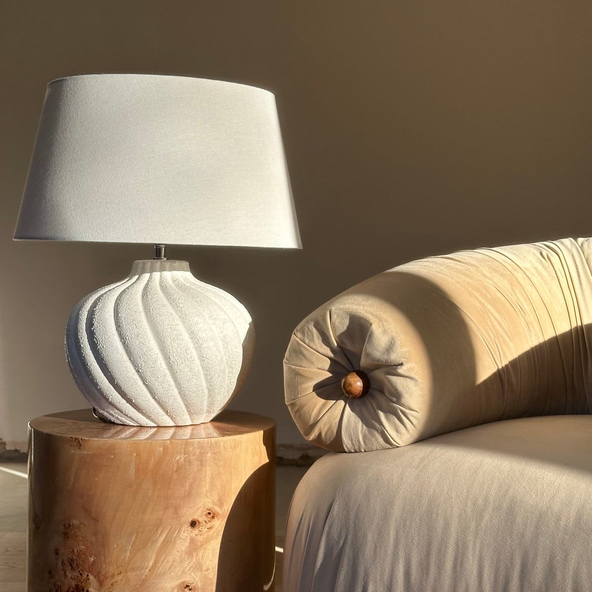 Textured ceramic based table lamp natural shade beside sofa