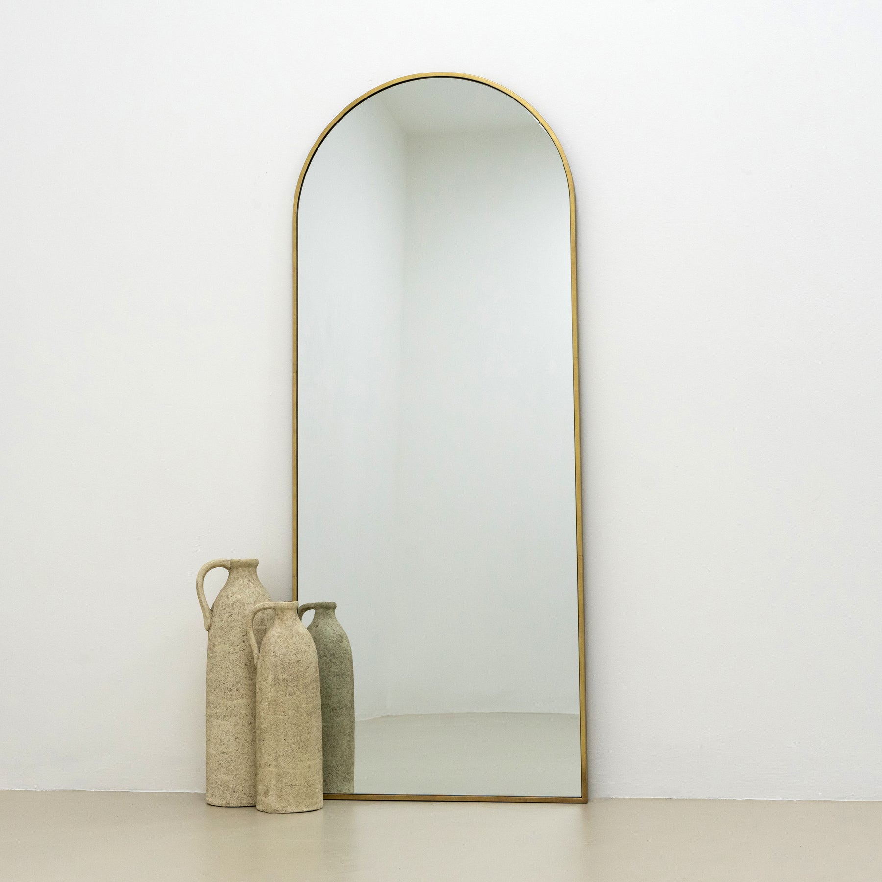 Full Length Gold Large Arched Metal Mirror beside ceramic vases