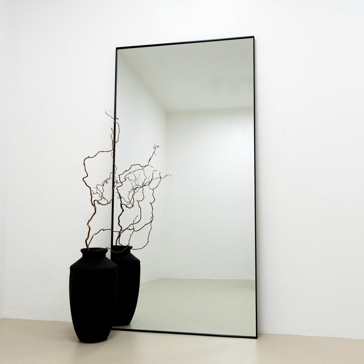 Full Length Black Extra Large Metal Mirror reflecting a black vase