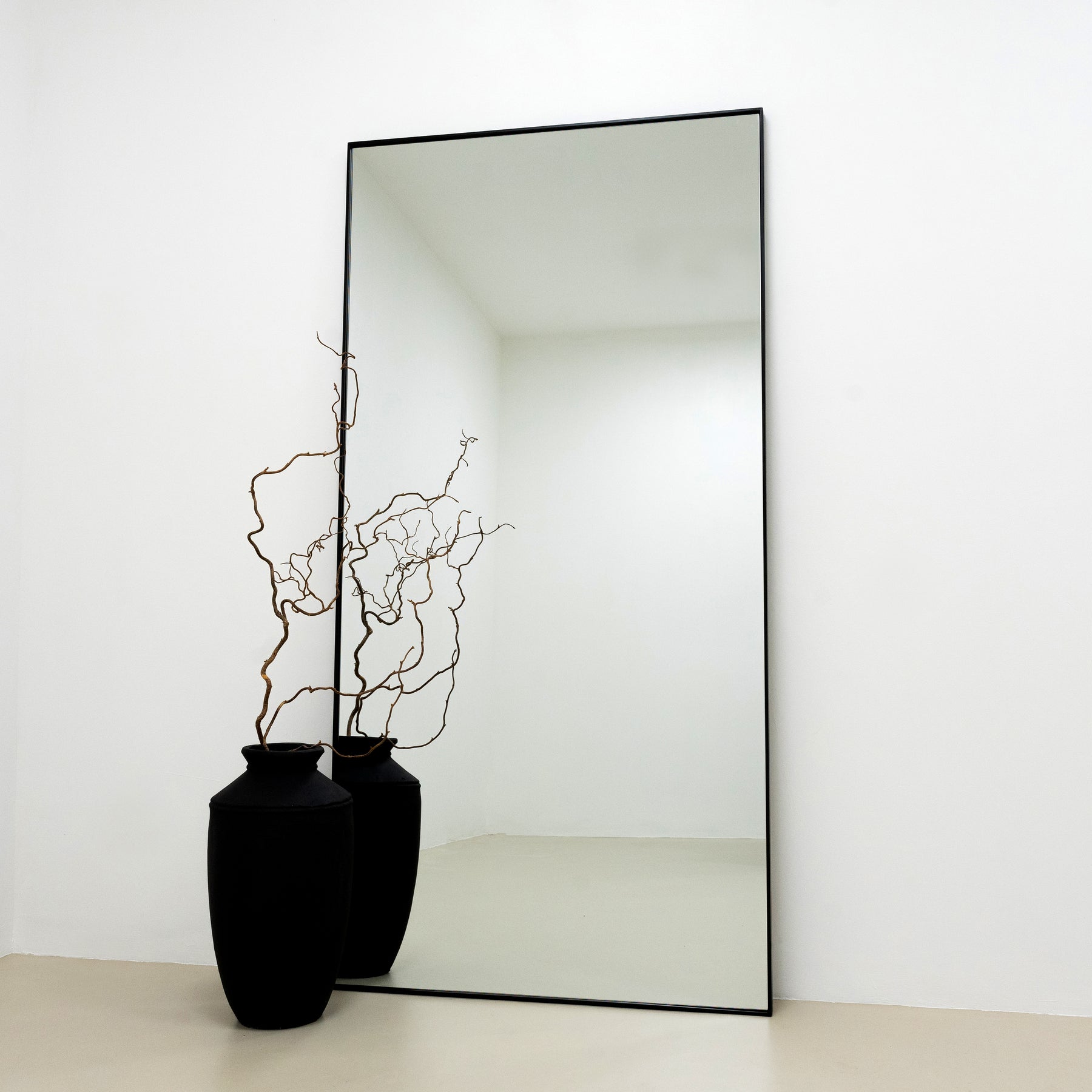 Full Length Black Extra Large Metal Mirror reflecting a black vase