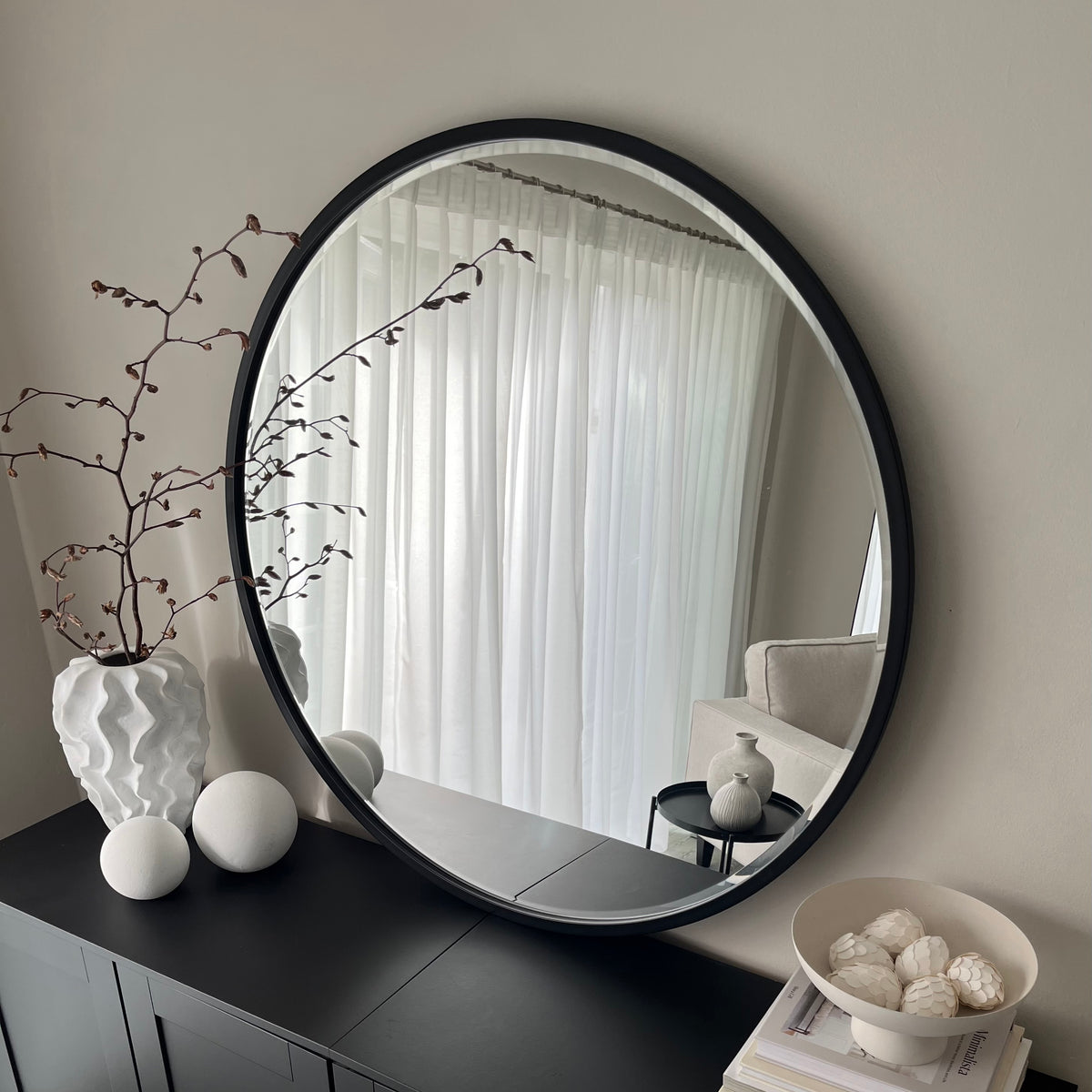 Black Metal Modern Round Wall Mirror leaning against wall