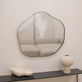 Black metal pond shaped irregular wall mirror displayed above console table