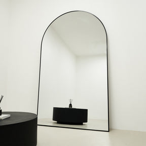 Black Full Length Arched Metal Mirror reflecting onyx table