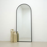 Champagne Full Length Arched Metal Mirror beside ceramic vases