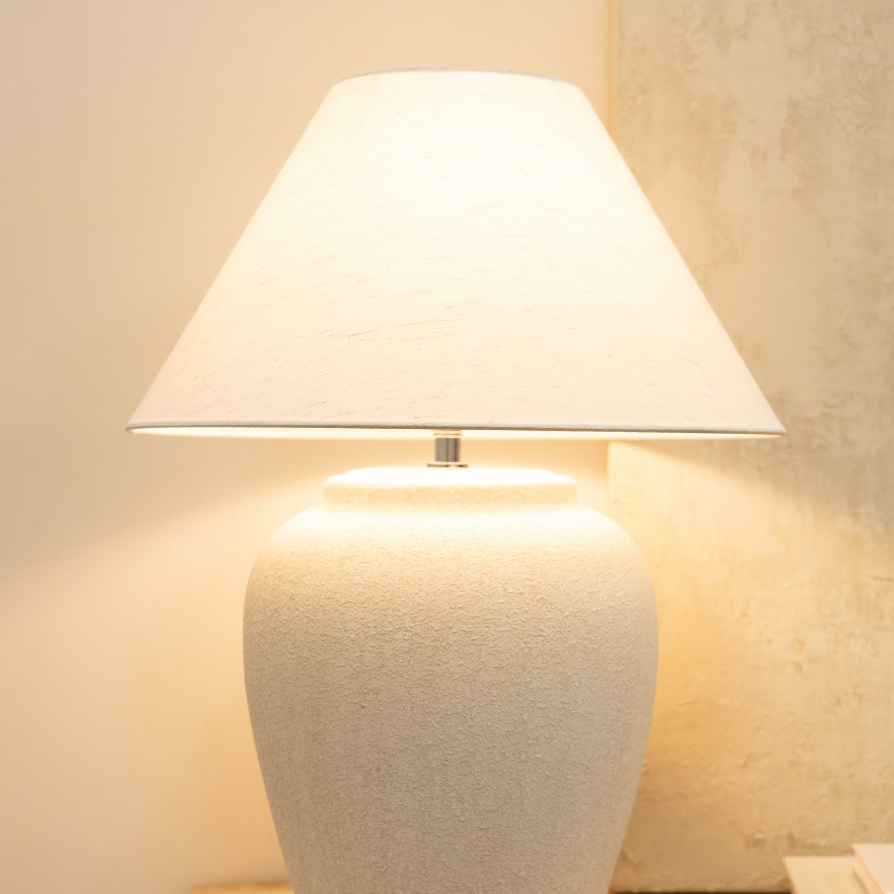 Detail shot of Stone Ceramic Coolie Shade Table Lamp emitting warm lighting