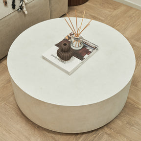 Large minimalist concrete round coffee table adorned with incense, book and ceramics