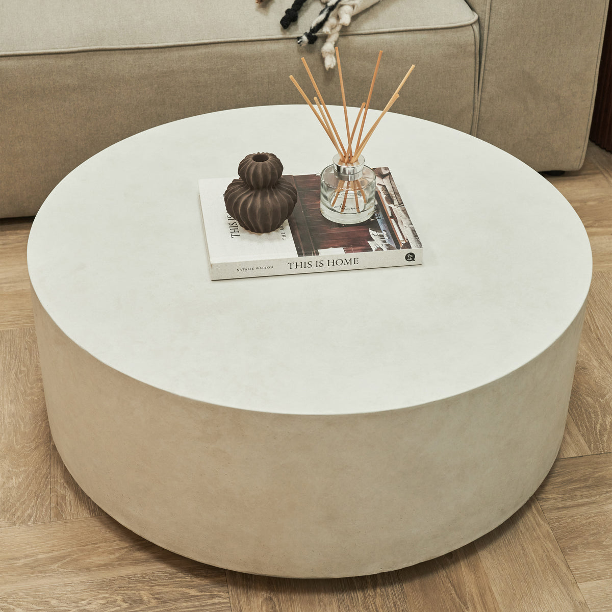 Large minimalist concrete round coffee table displayed beside sofa