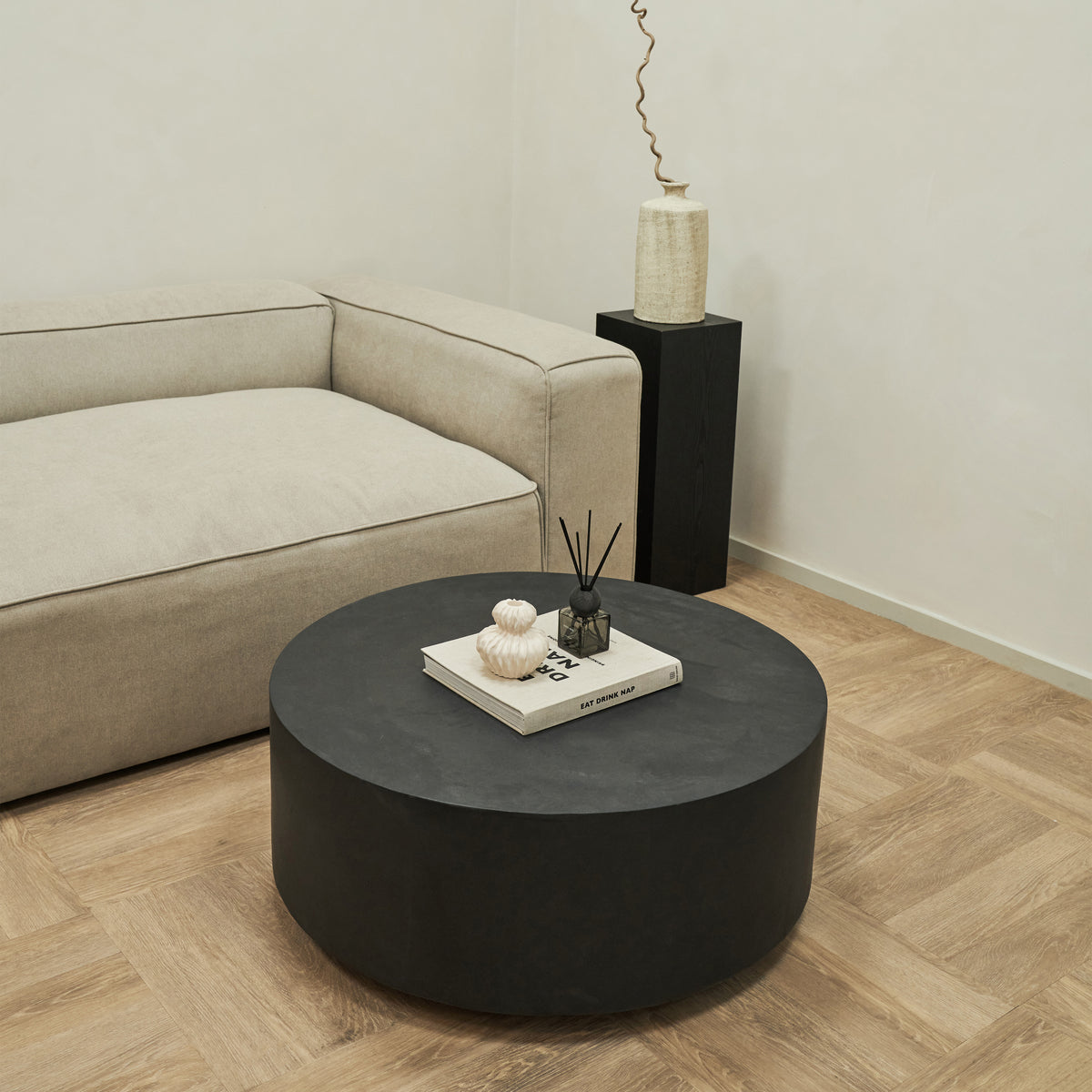 Large minimalist round black coffee table beside sofa