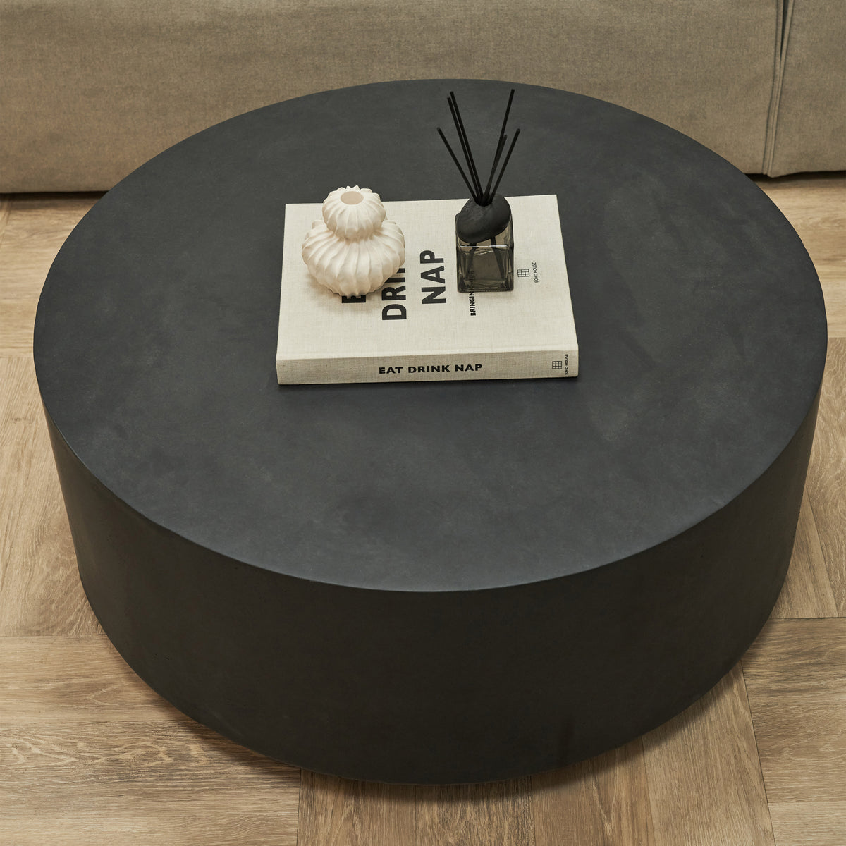 Large minimalist round black coffee table beside sofa