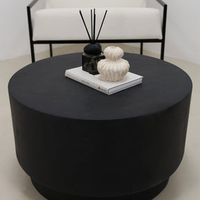 Minimalist round black coffee table beside chair