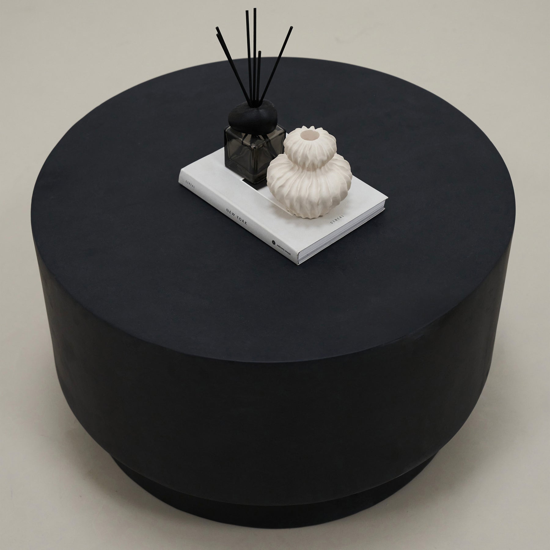 Minimal onyx round coffee table adorned with book, incense, and ceramics