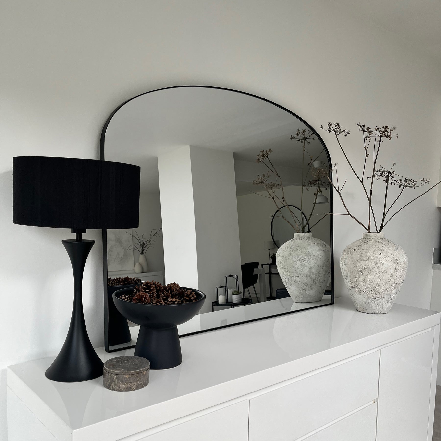 Black metal overmantle large wall mirror displayed on console table