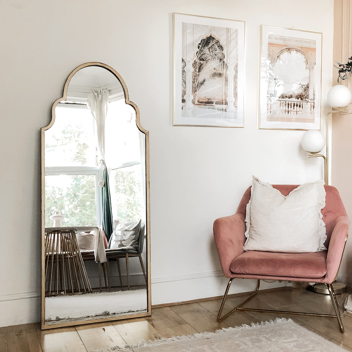 Gold industrial arched full length metal mirror leaning against wall