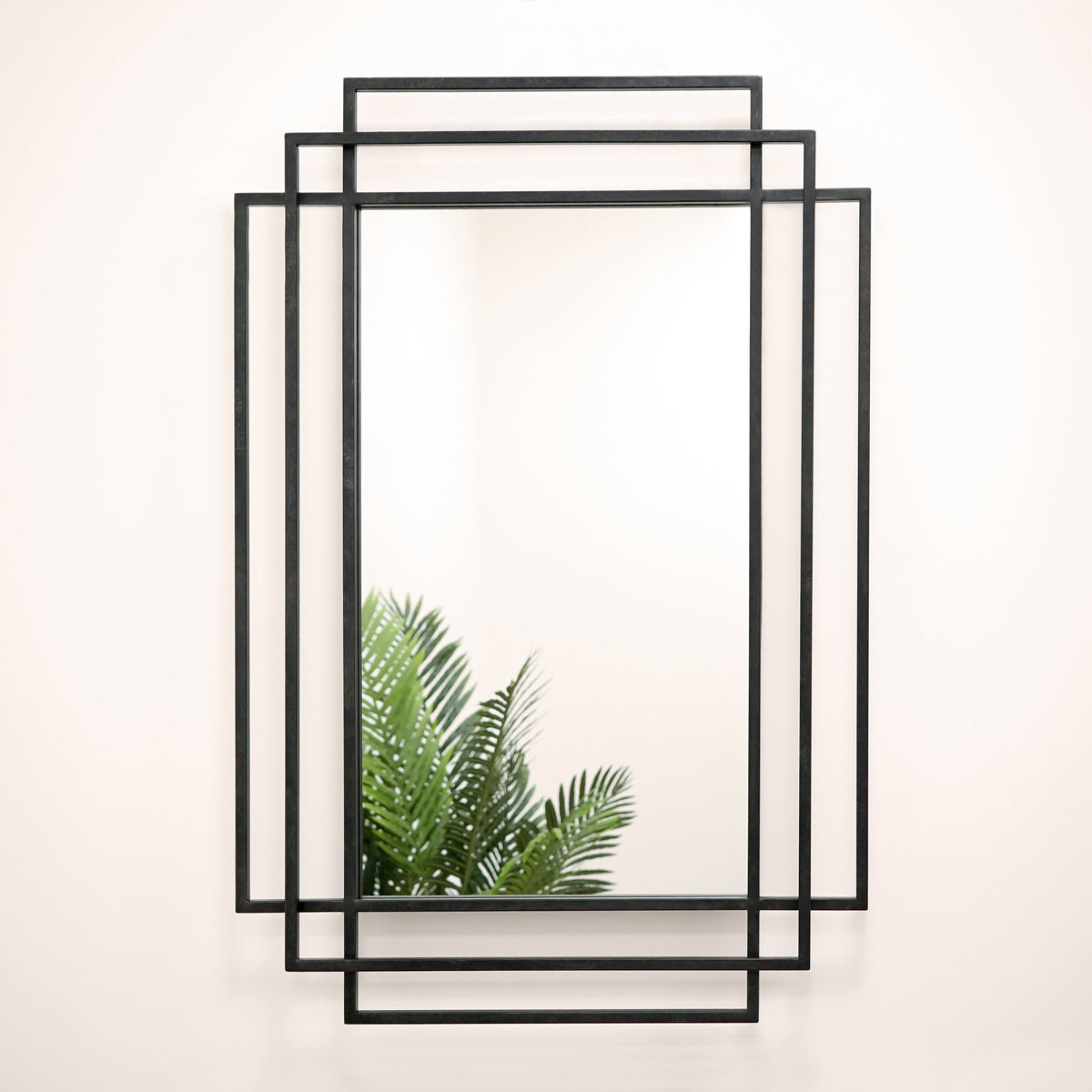 Black rectangular art deco metal mirror displayed on wall