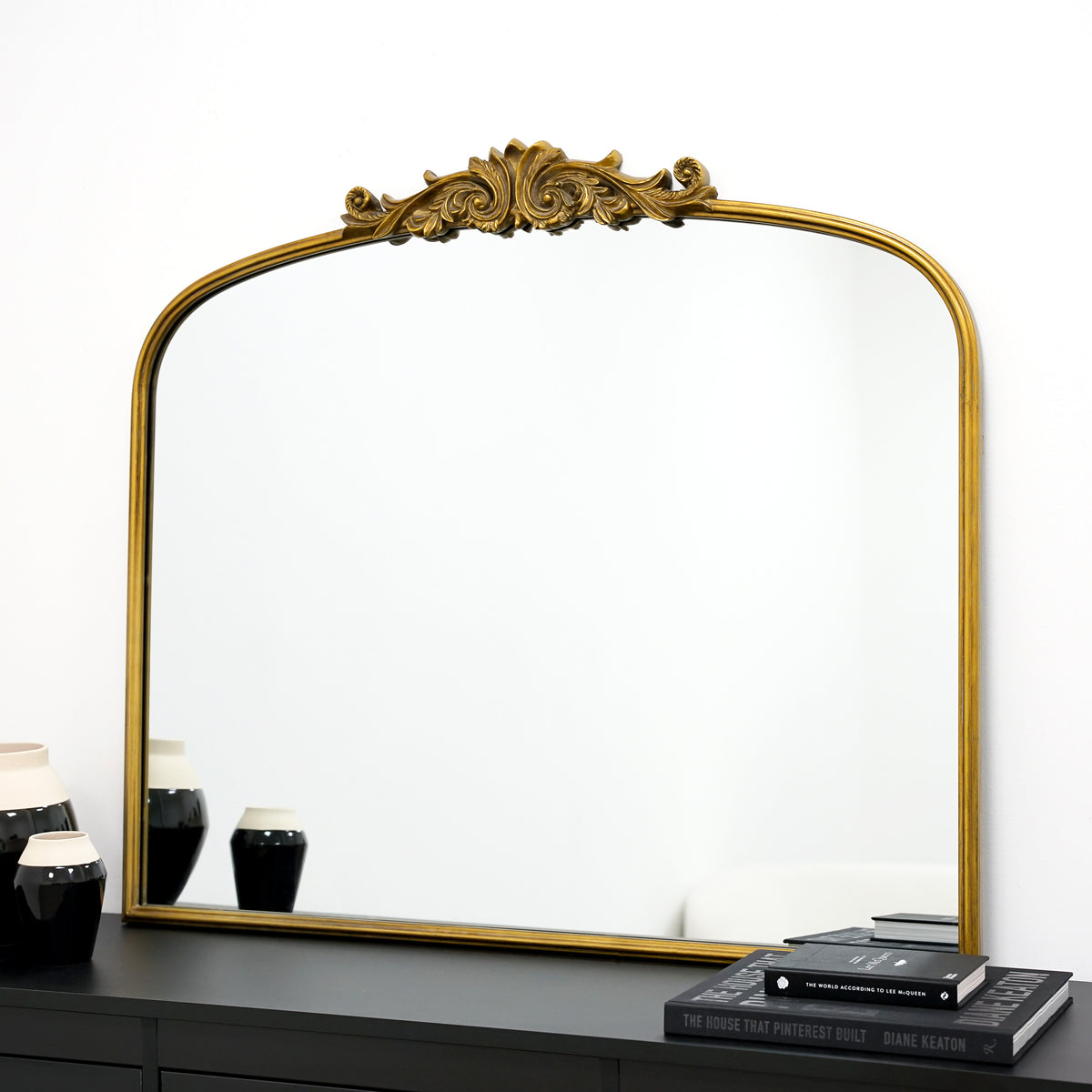 Gold arched ornate metal overmantle mirror on console table