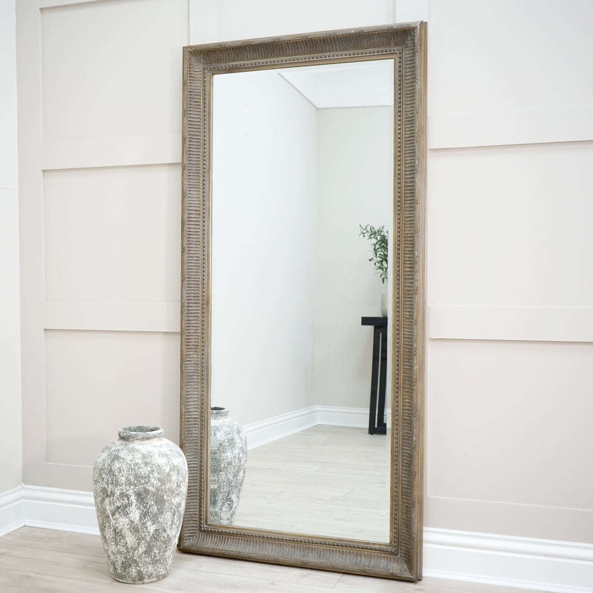 Full length washed wood rectangular mirror leaning against wall