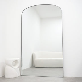 Full length black extra large metal mirror leaning against wall