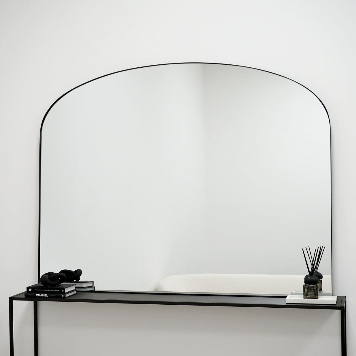 Black metal overmantle large wall mirror displayed on console table