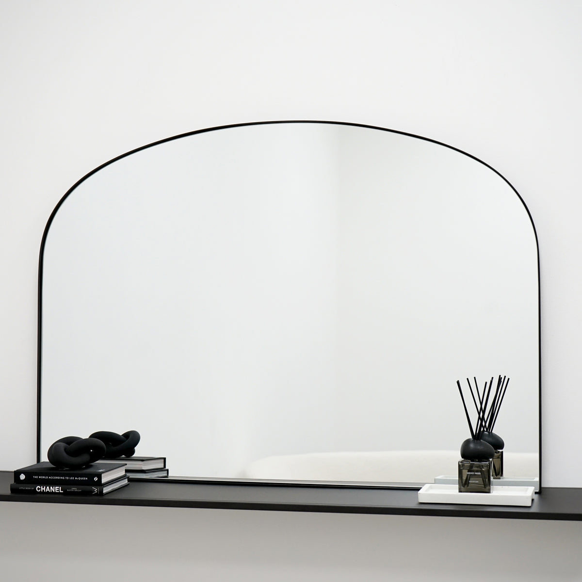 Black metal overmantle wall mirror displayed above console table