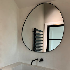 Black metal pond shaped irregular wall mirror displayed in bathroom