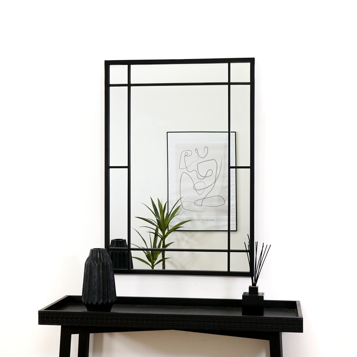 Black industrial rectangular metal mirror displayed above console table