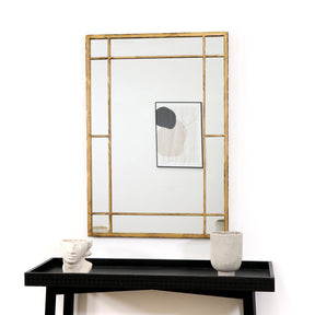 Gold industrial rectangle metal mirror displayed above console table