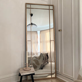 Gold industrial full length metal mirror leaning against wall