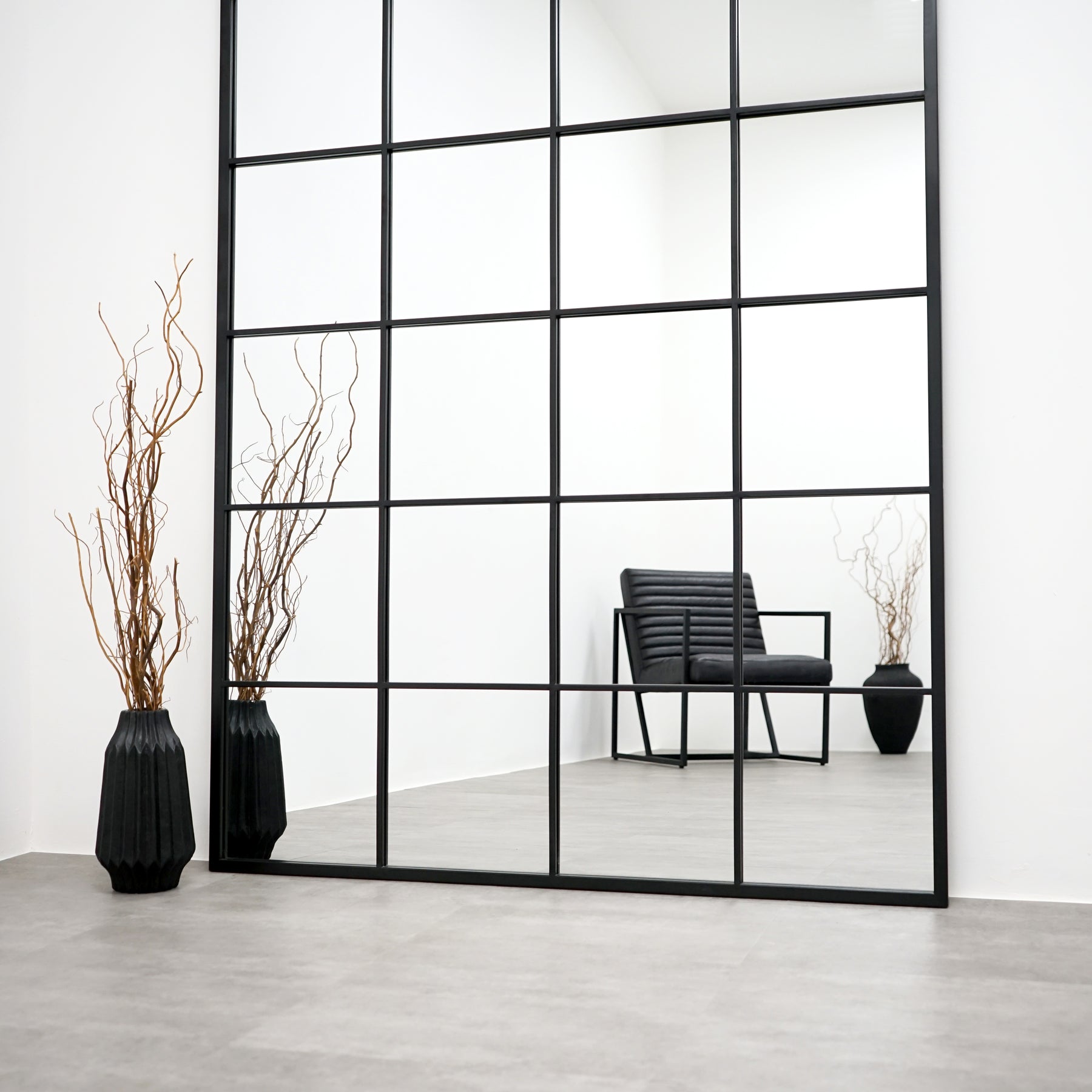 Full length XXL black industrial metal window mirror beside vase