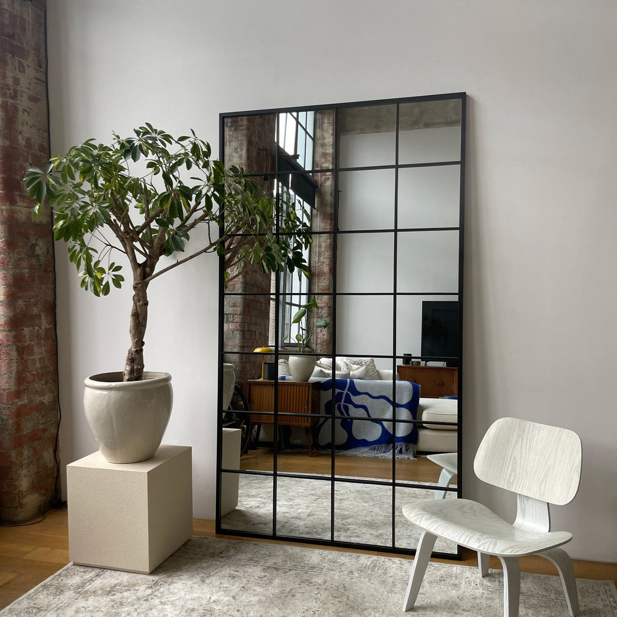 Full length extra large black industrial metal window mirror leaning against wall