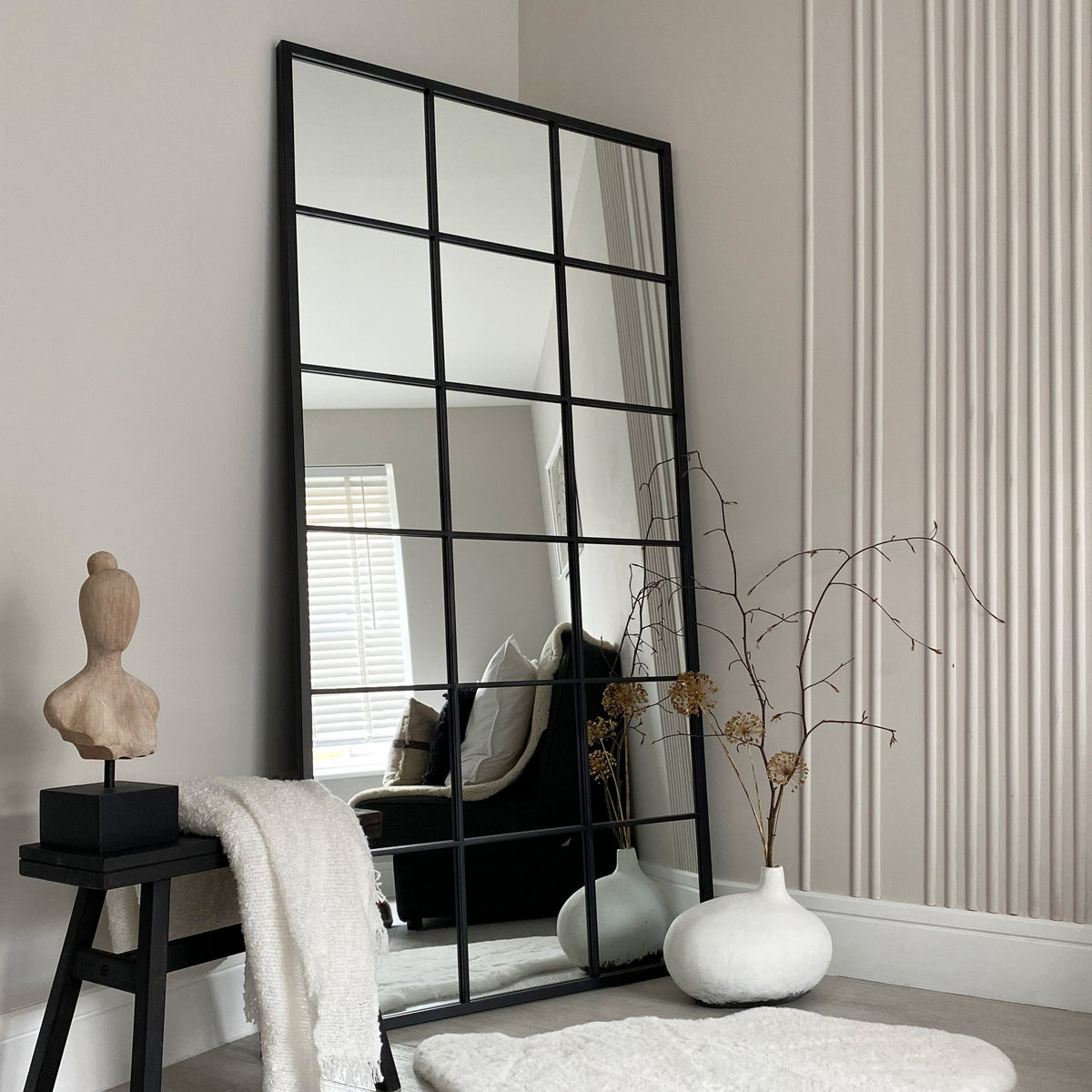 Full length large black metal window mirror in minimalist setting