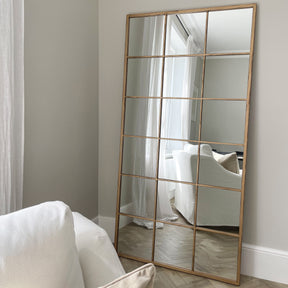 Full length large gold industrial metal window mirror leaning against wall in lounge