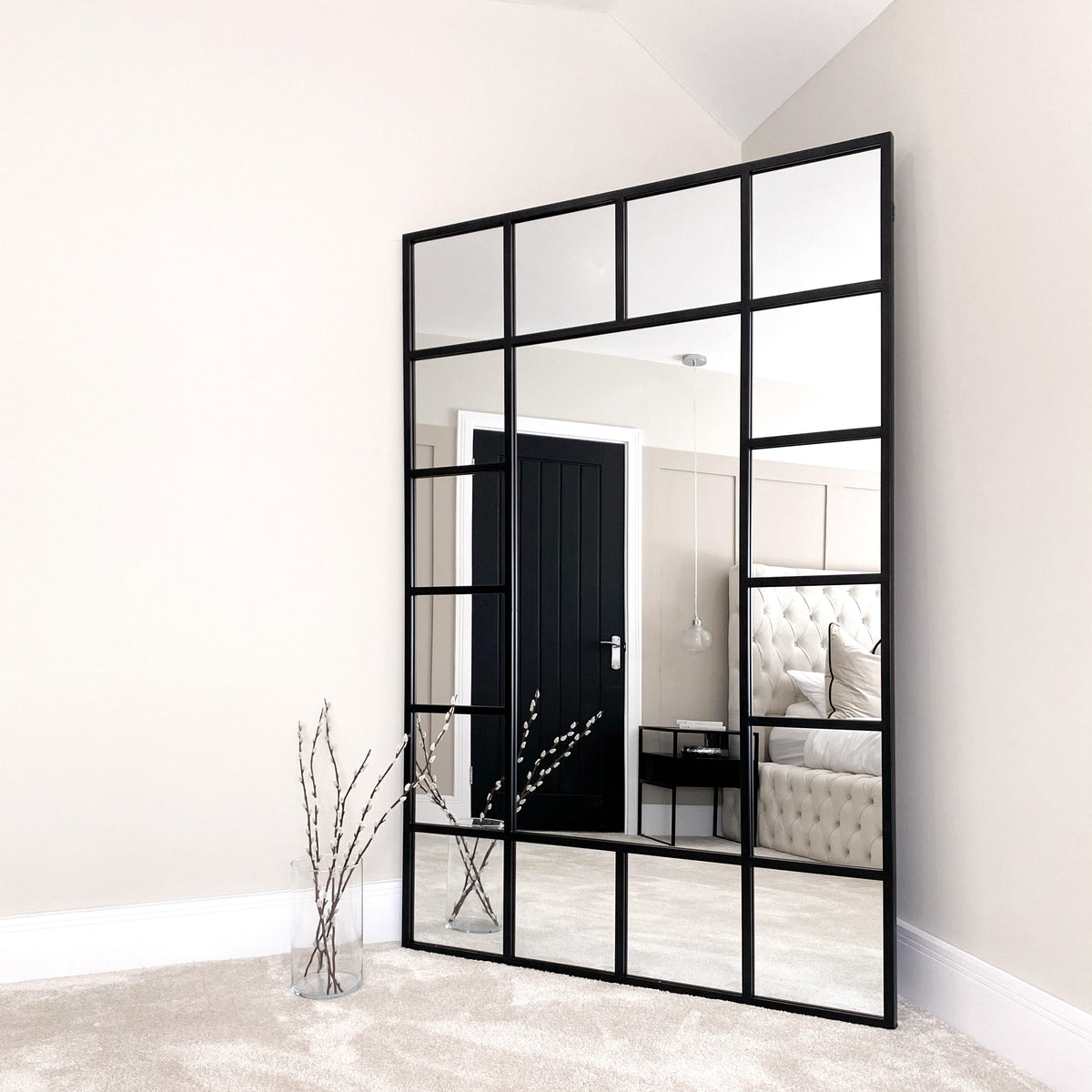 Black industrial full length metal window mirror in room corner