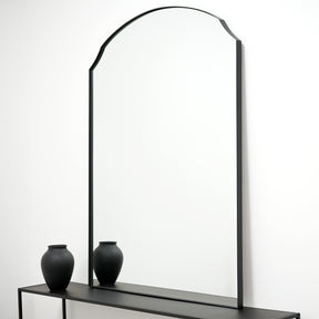 Black Arched Metal Overmantle Wall Mirror beside ceramic vase