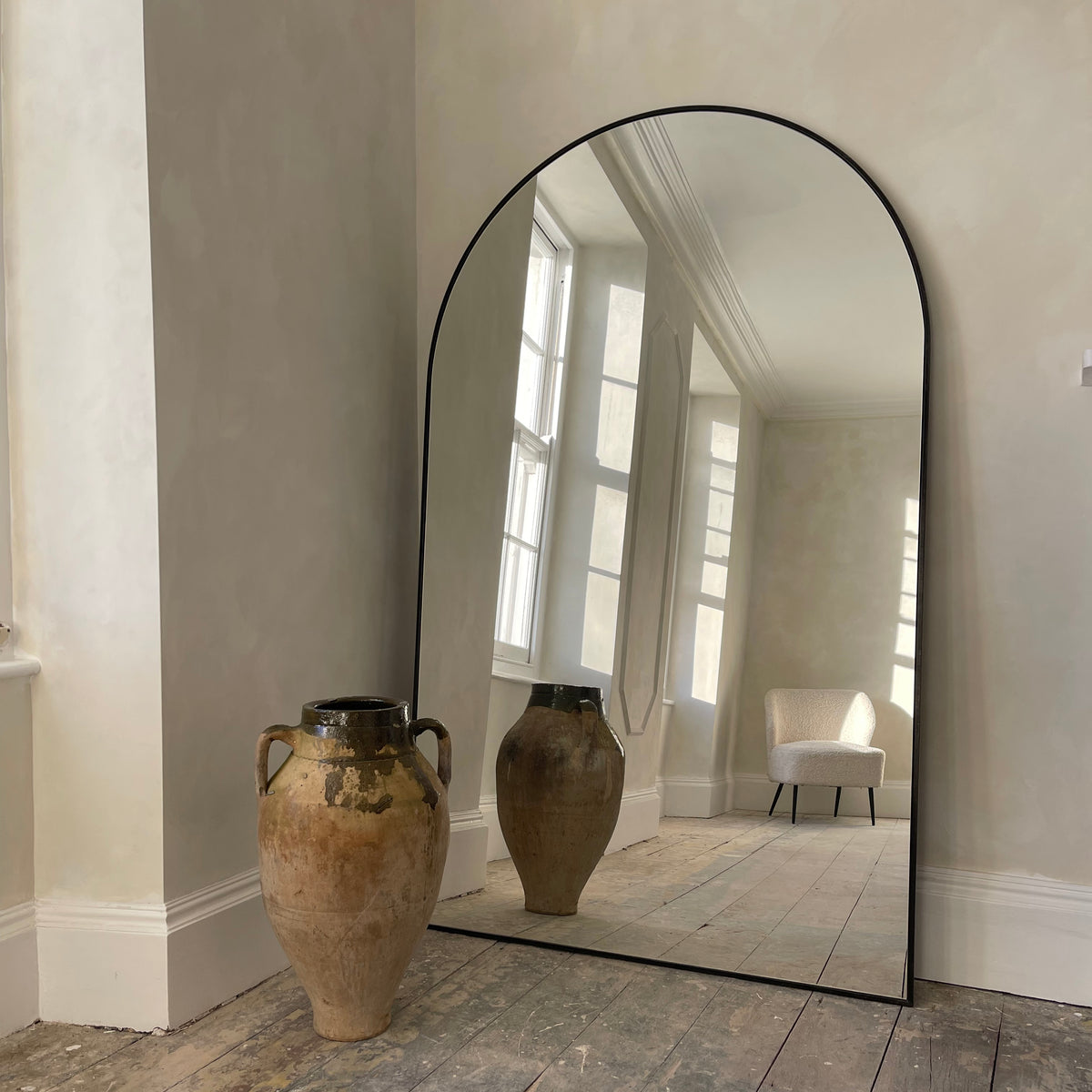 Black Full Length Arched Metal Mirror beside ceramic vase