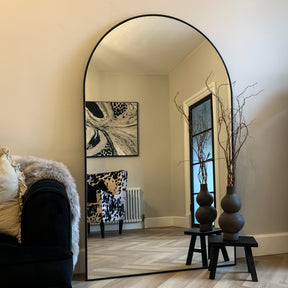 Black Full Length Arched Metal Mirror beside sofa