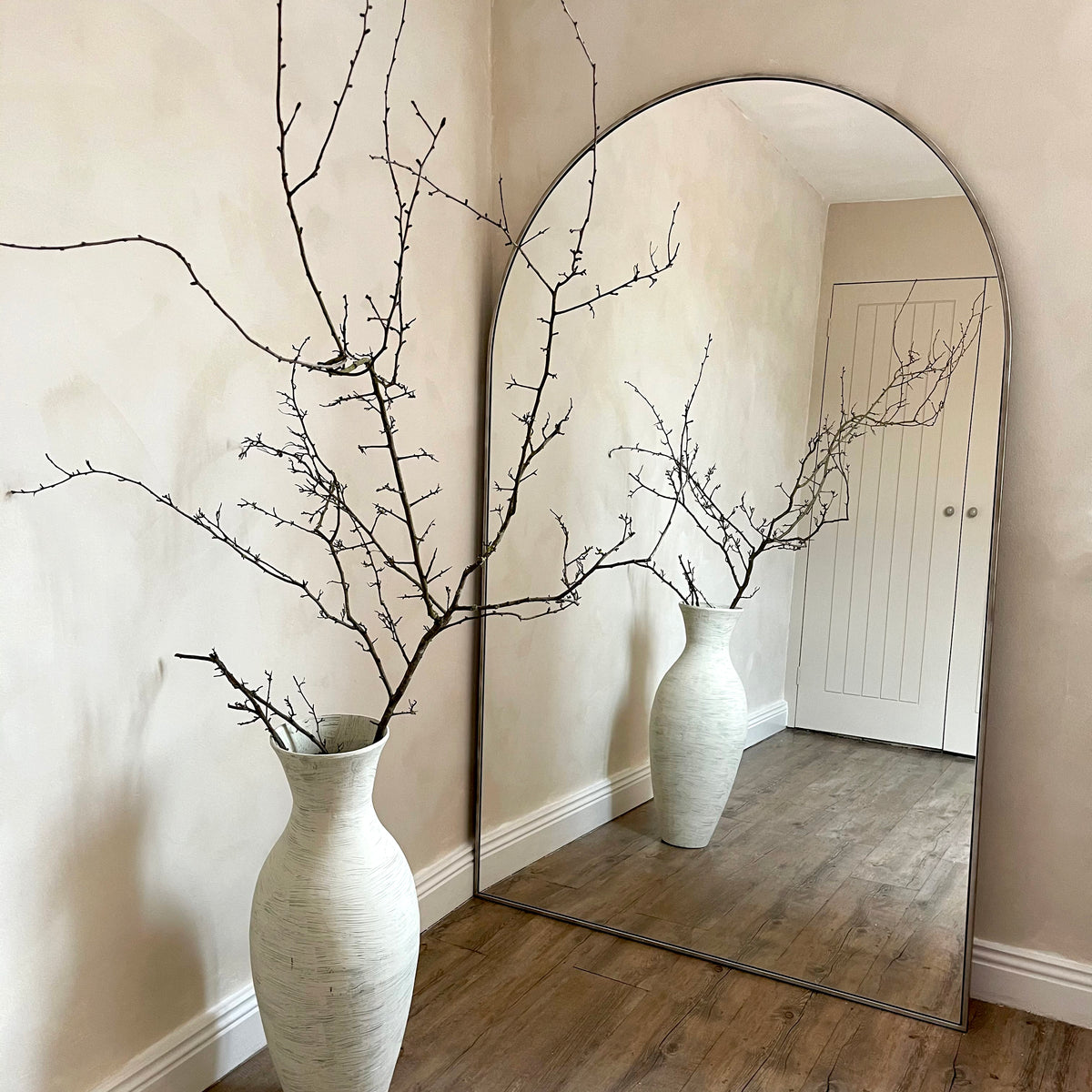 Champagne Full Length Arched Metal Mirror leaning against wall beside vase
