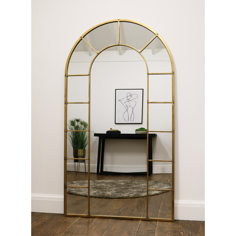 Gold industrial arched full length metal mirror reflecting lounge