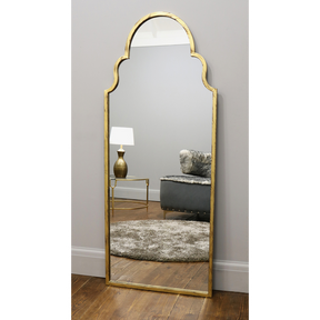 Gold industrial arched large metal mirror leaning against wall