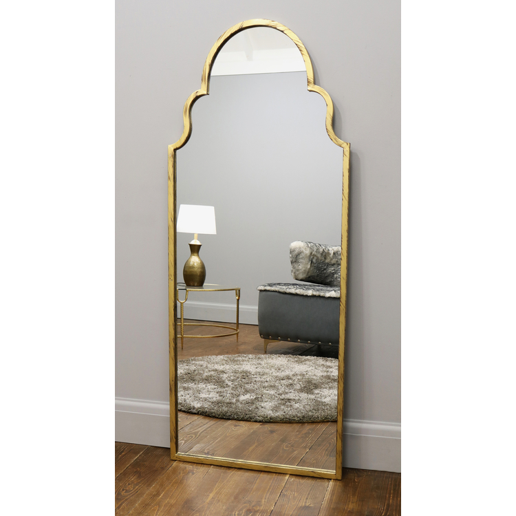 Gold industrial arched large metal mirror leaning against wall
