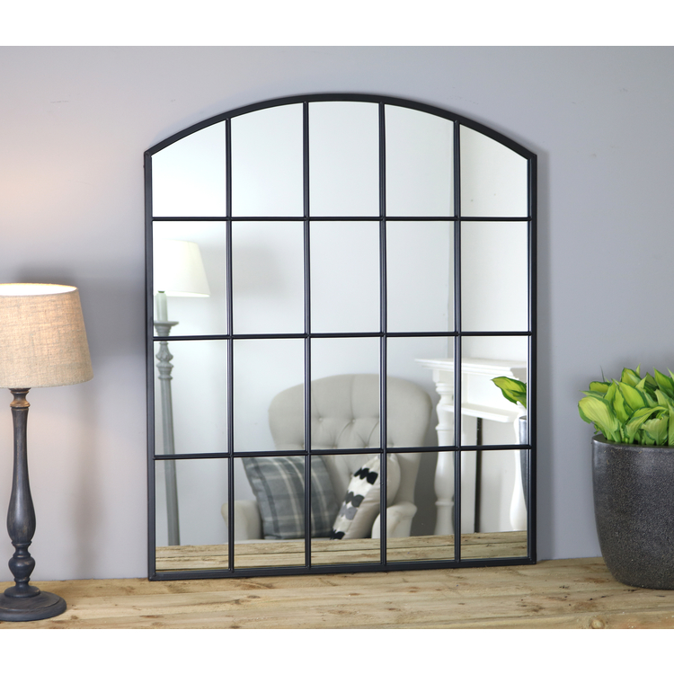Black industrial arched metal window mirror displayed on wooden table