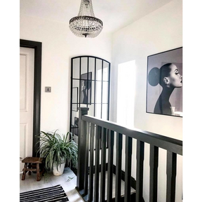 Full length black metal window mirror displayed on staircase wall