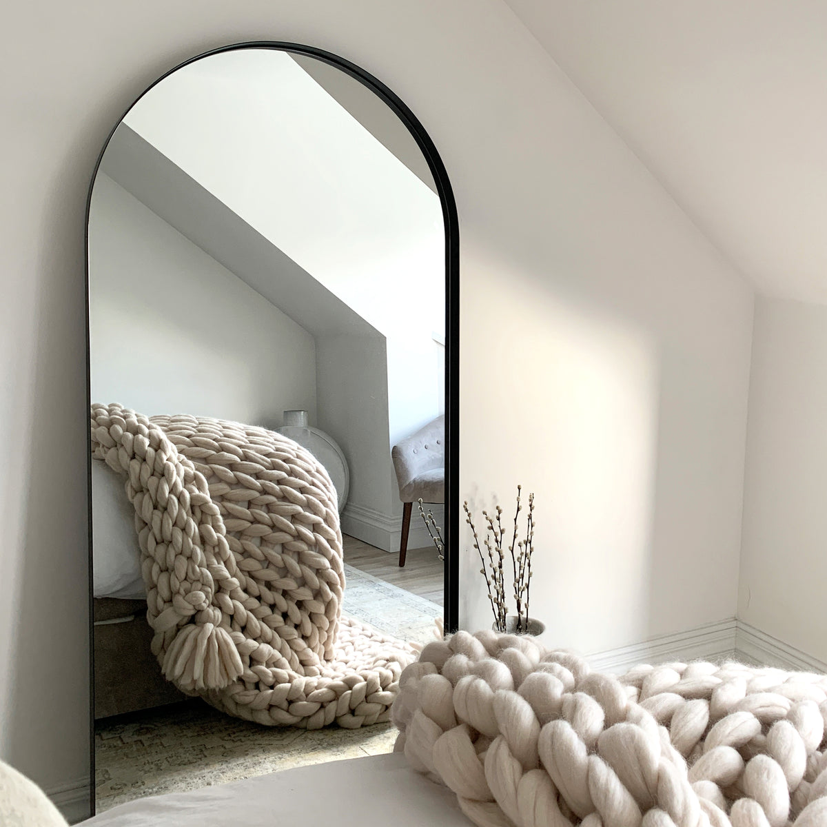 Full length arched black large metal mirror leaning against wall